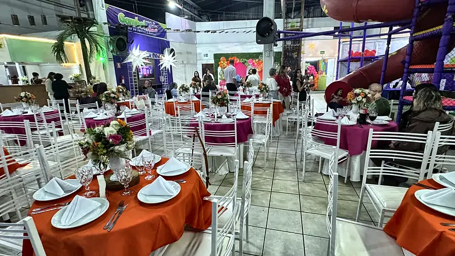 Mesas postas com toalhas laranja e arranjos de flores